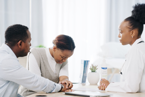 Frozen embryo transfer cost in Nigeria: A dark-skinned couple receives a transparent medical and financial consultation from a professional Black fertility doctor at a clinic.